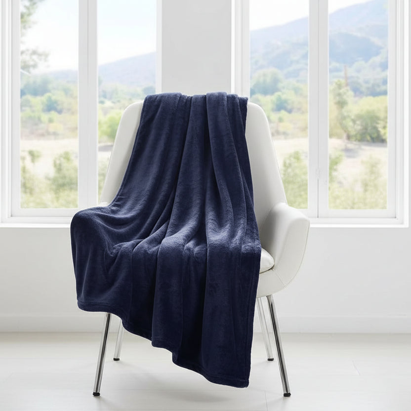 Navy blanket draped over a white chair in a room with large windows showing a scenic view.