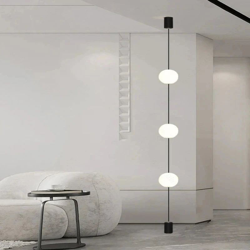 Contemporary lounge space with 3-head floor-to-ceiling LED globe light next to a rounded white armchair