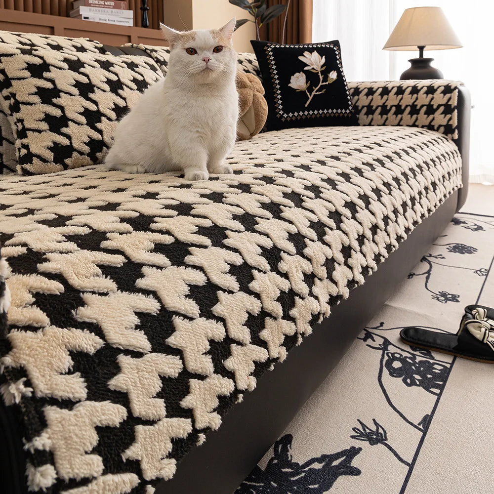 White cat sitting on a black and white patterned sofa in a living room.