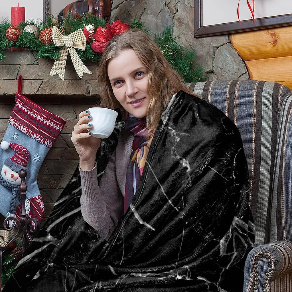  Woman sitting by a fireplace wrapped in a black marble print throw blanket