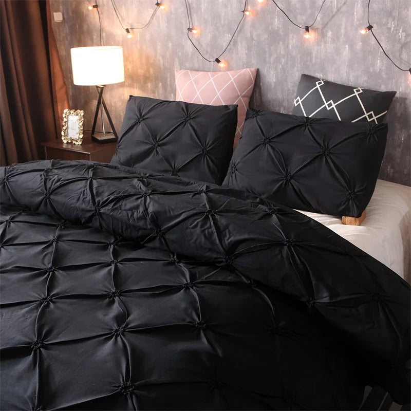 Black pintuck duvet set with matching pillowcases dressed on a double bed in a warm contemporary bedroom
