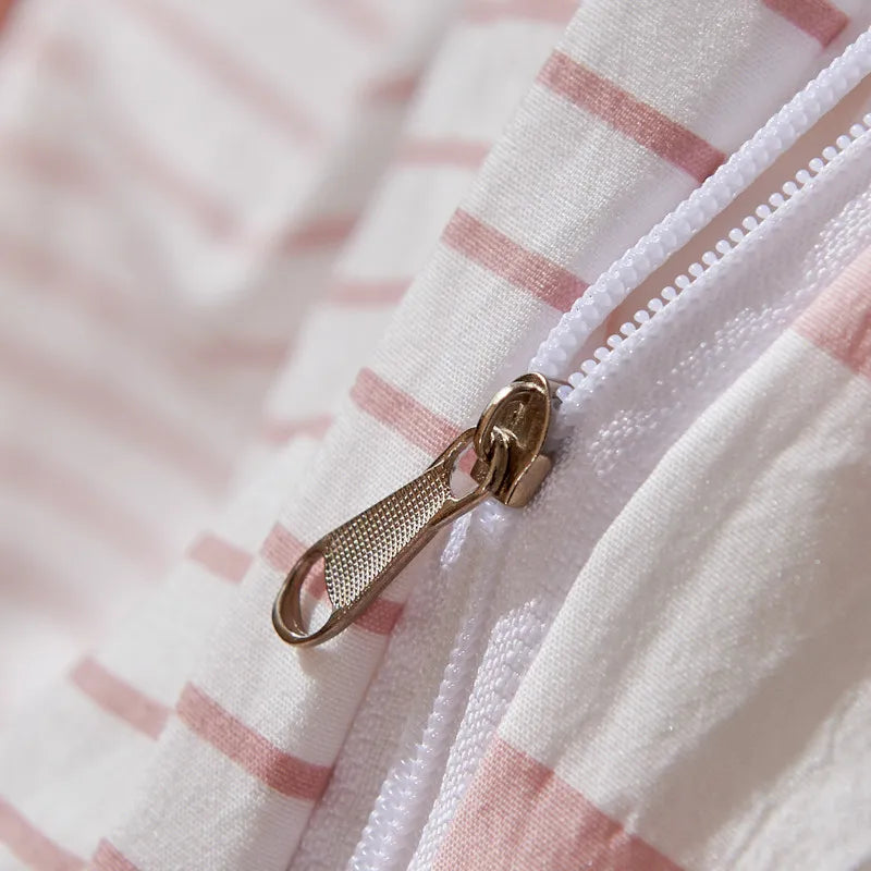 Close-up of a gold zipper on a white and pink striped fabric background