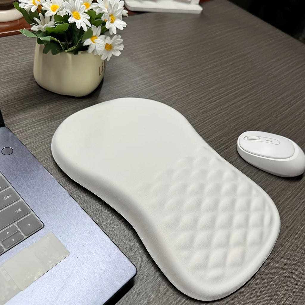 White wrist rest on a desk with a laptop, mouse, and flowers in the background