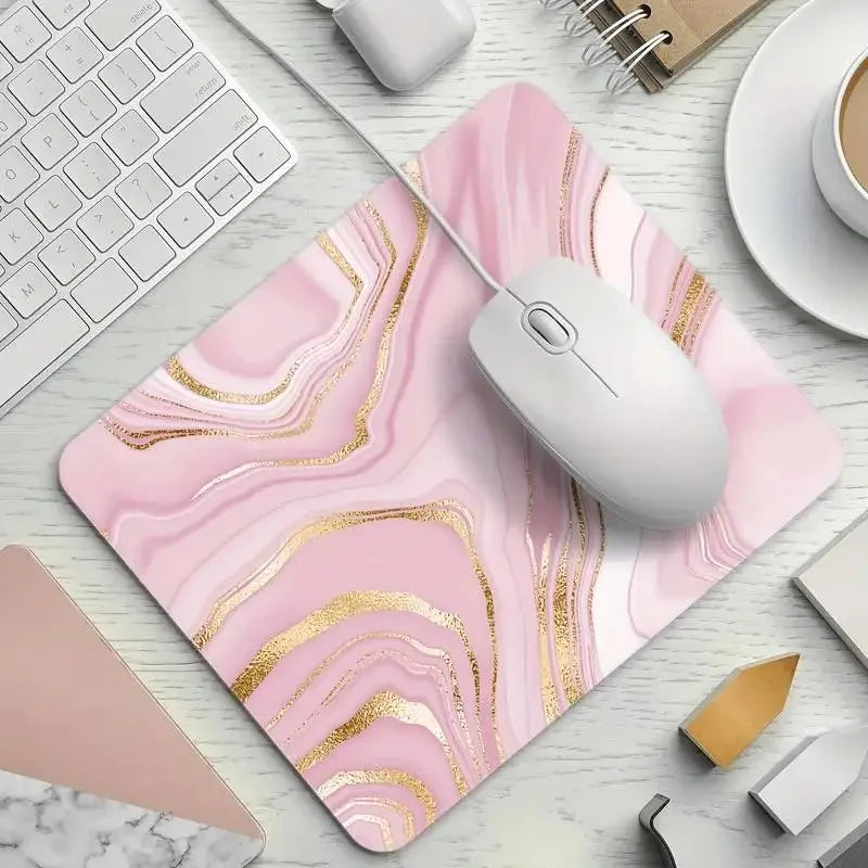 Pink marble mouse pad with gold accents on a desk with a keyboard and mouse.