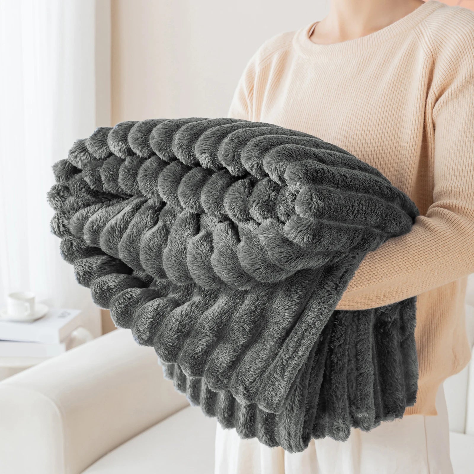 Person holding a large gray blanket in a home setting