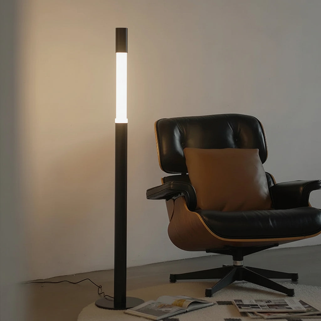 Minimalist Gun Black floor lamp styled in a modern living room next to a designer chair.