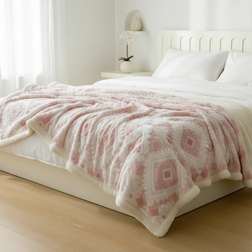 Pink patterned blanket on a bed in a bright bedroom