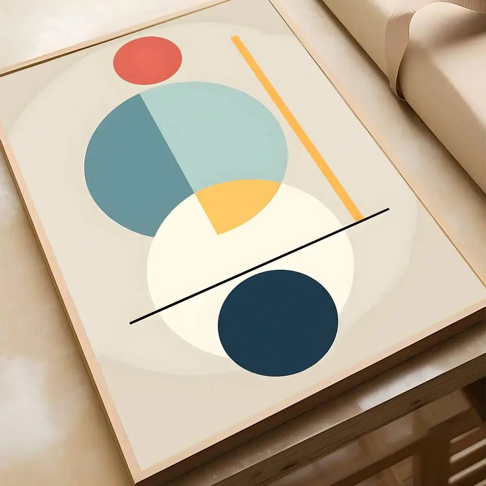 Soft abstract canvas print with layered blue, teal, and navy circles with a yellow arc and red dot on a warm cream background, in a wood frame.