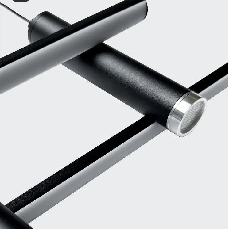 Modern linear pendant light fixture with a matte black cylindrical shade and a polished silver metal end cap, shown in a close-up angled view against a light grey background.