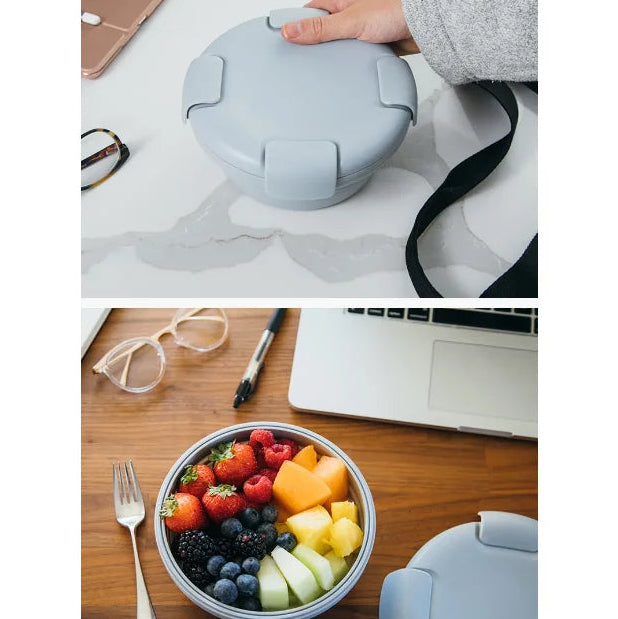 Reusable lunch container with a lid, filled with fruit, on a desk.