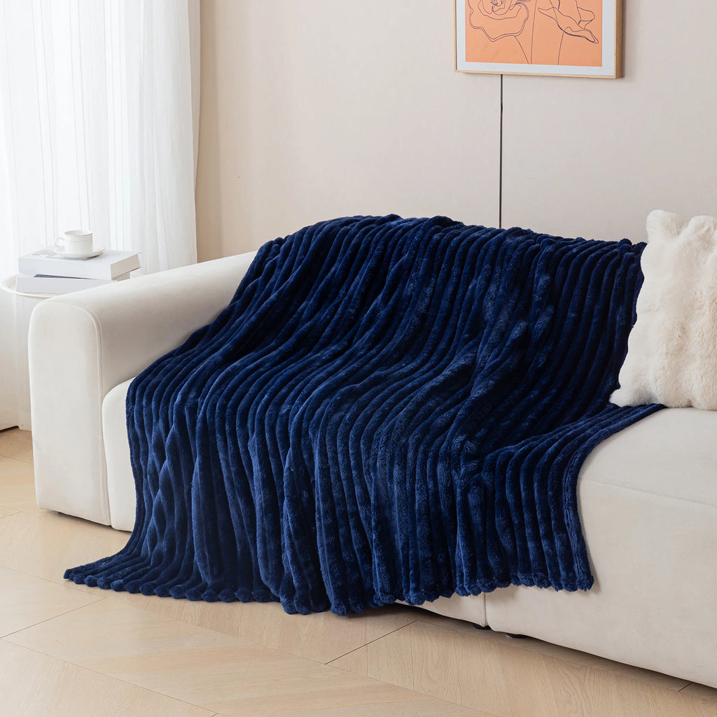 Navy blue blanket draped over a white sofa in a living room setting.