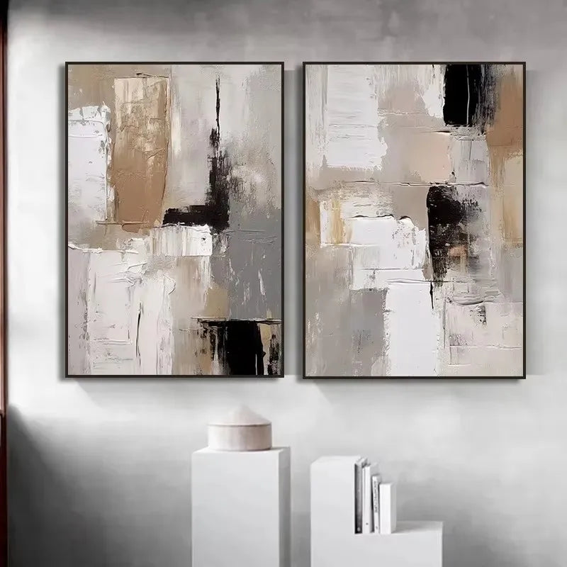 Two abstract art pieces in black, white, and beige frames on a gray wall.