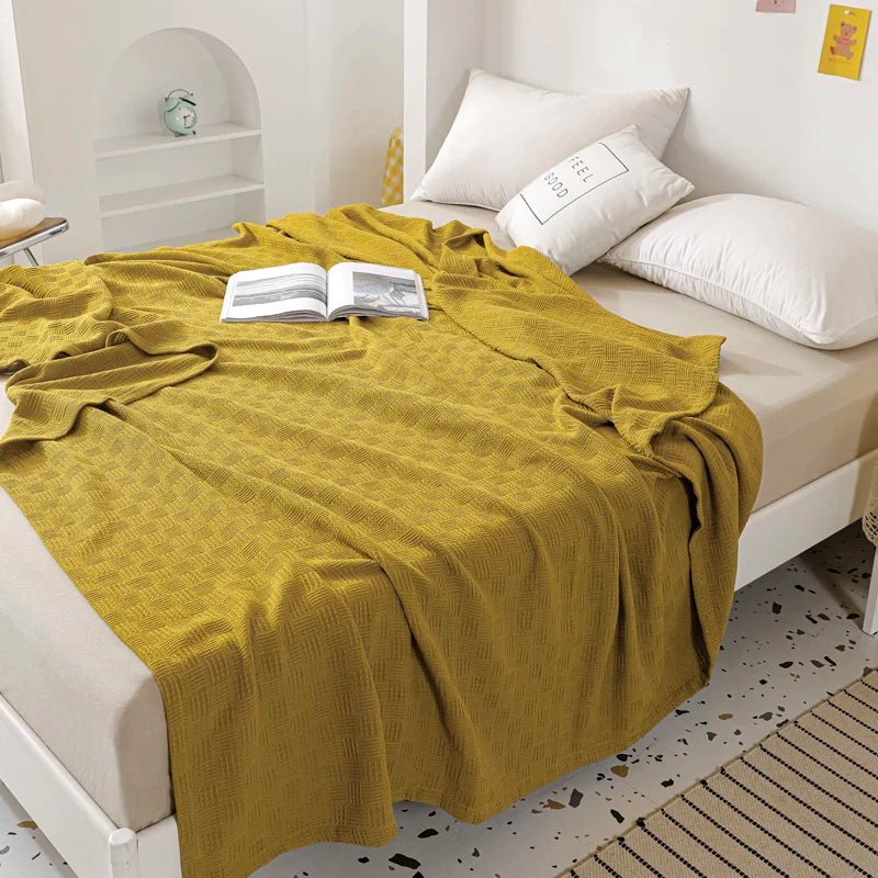 A olive cotton knit throw blanket with textured weave pattern.
