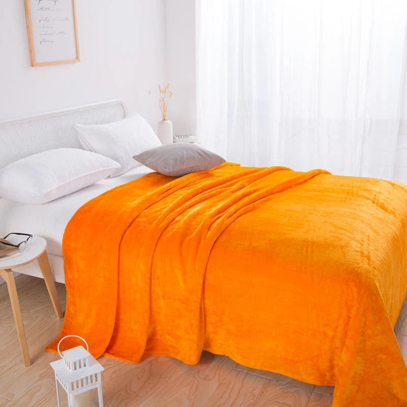 Orange plush blanket draped across a white bed with pillows