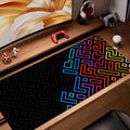 Black desk mat with bright neon maze pattern in blue, pink, orange, and yellow