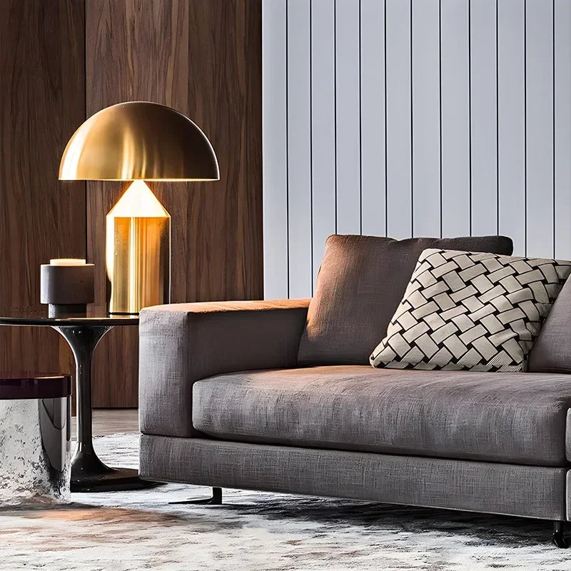 Gray sofa with a gold lamp and decorative pillow in a modern living room.
