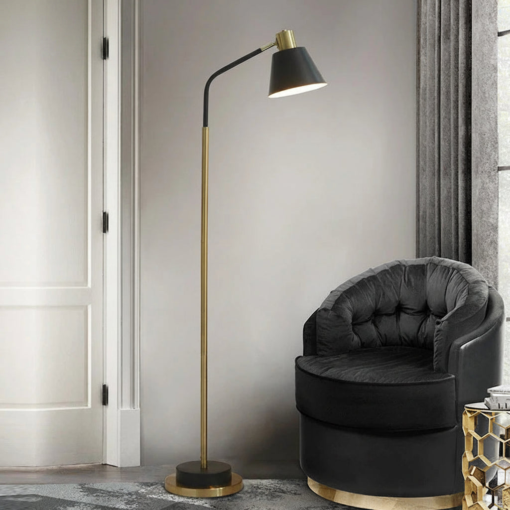 Black Nordic Floor Lamp — Black Nordic-style metal floor lamp with gold-tone stem, angled shade, and round base, shown beside a dark accent chair.