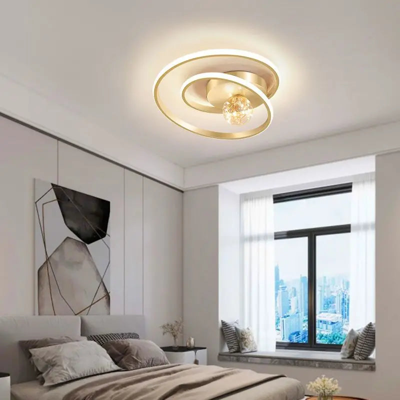 Gold Nordic spiral ceiling light with amber glass globe installed above a modern bedroom with warm ambient lighting
