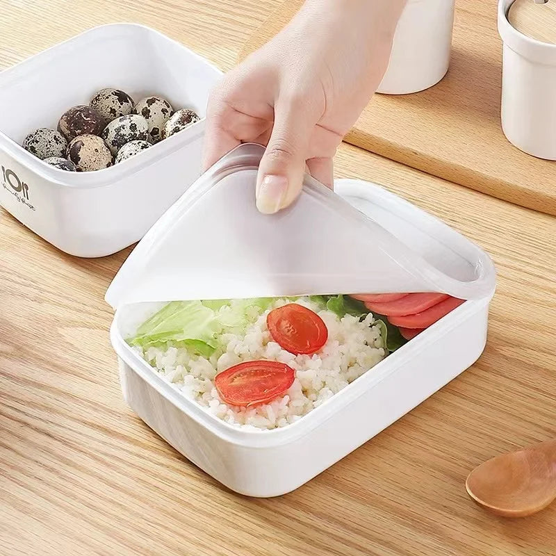 White lunch box with food on a wooden table