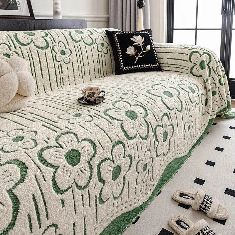 Cream sofa throw with green floral pattern, textured tatting weave, draped over a modern three-seater sofa in a neutral living room.