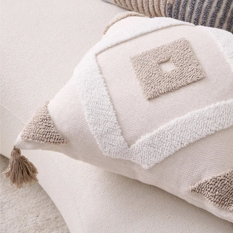 Close-up of a textured pillow with a tassel on a light-colored surface