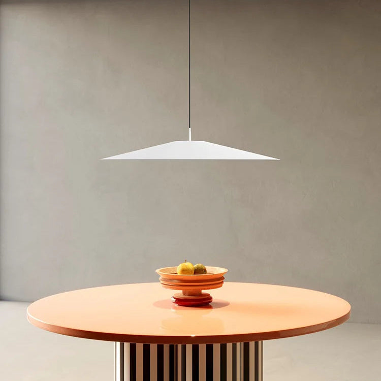 White minimalist pendant light above a round orange table with a fruit bowl