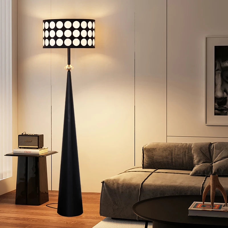 Modern black floor lamp in a living room setting with a sofa and side table.