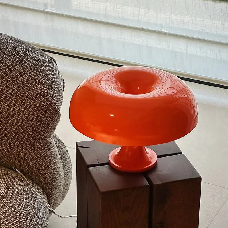 Orange mushroom lamp on a wooden side table next to a textured grey chair.
