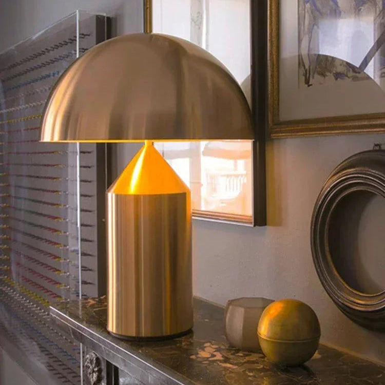 Gold table lamp on a decorative surface with framed artwork in the background
