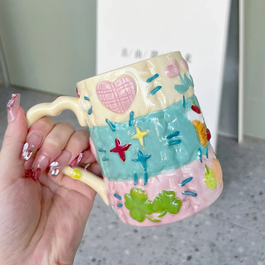 Colorful ceramic mug with decorative patterns held by a hand.