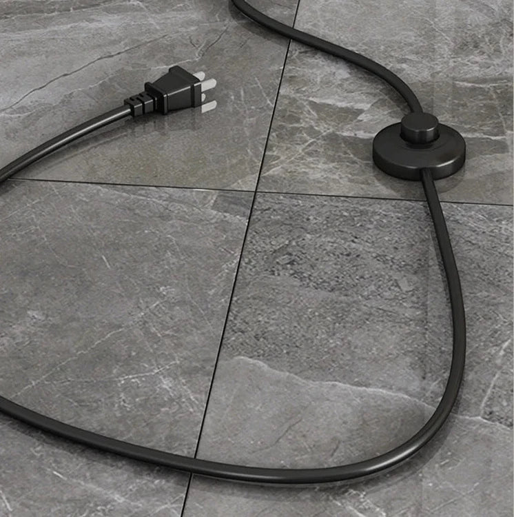 Close-up of black foot pedal switch and power cord on marble floor