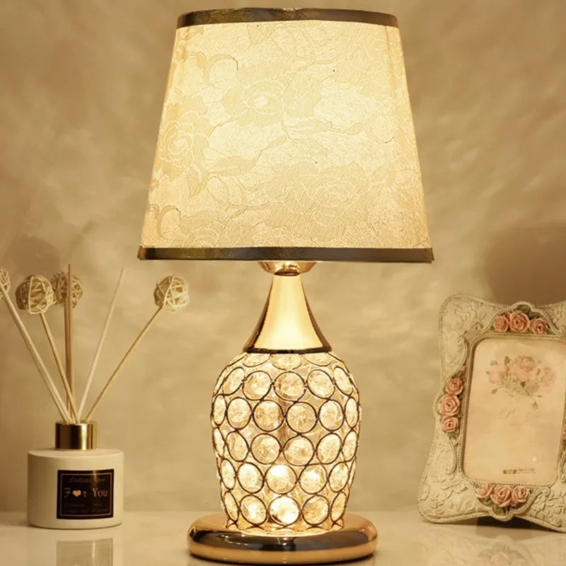 Elegant gold bedside lamp featuring intricate vine patterns on a white fabric lampshade.