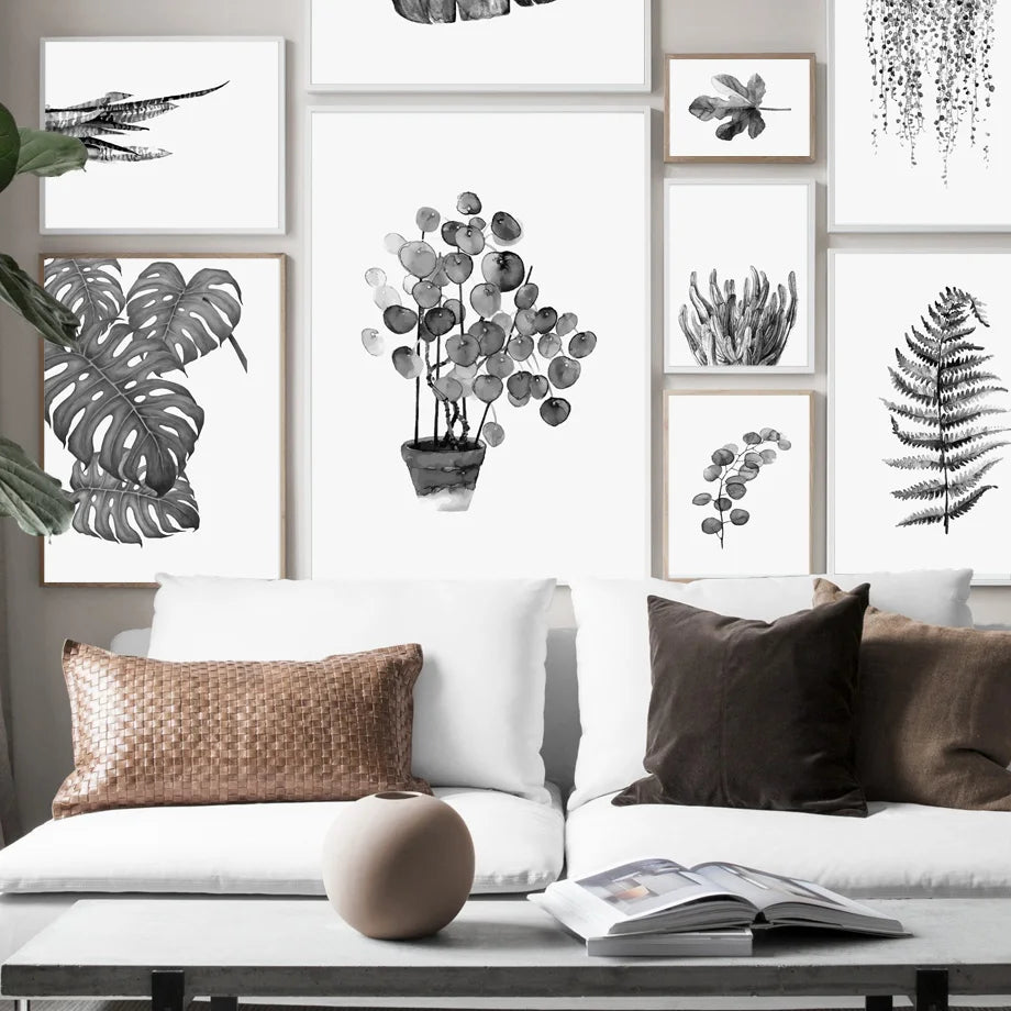 Living room with white sofa, decorative pillows, and framed botanical prints on the wall.