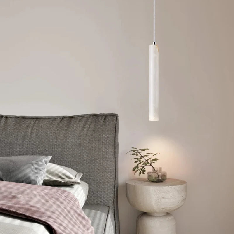 Modern bedroom with a gray headboard, pink blanket, and a pendant light.