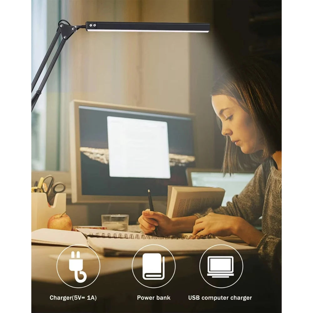 Person working at a desk with a adjustable desk lamp, computer, and various items.
