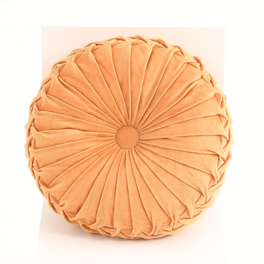 Round pleated cushion in a peach colour on a white background