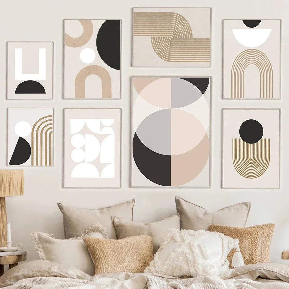 Geometric wall art prints on a wall above a bed with pillows.
