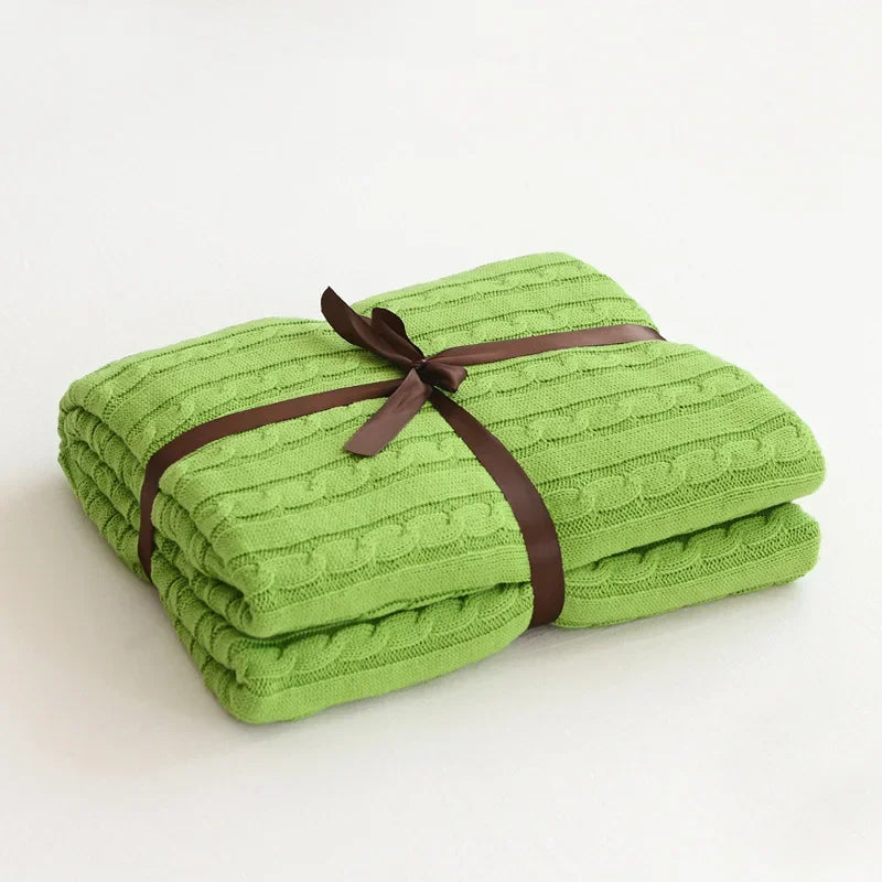 Folded green blanket with a brown ribbon on a white background