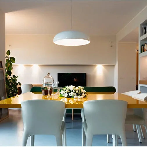Modern dining room with a white pendant light, table, and chairs.