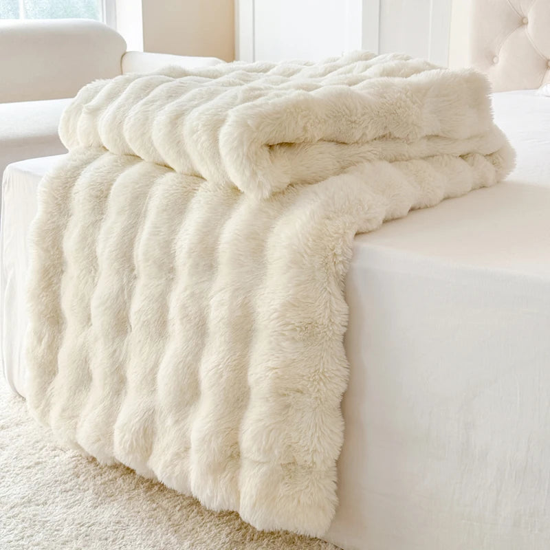 Cream-colored fluffy blanket draped over a white sofa in a bright room.