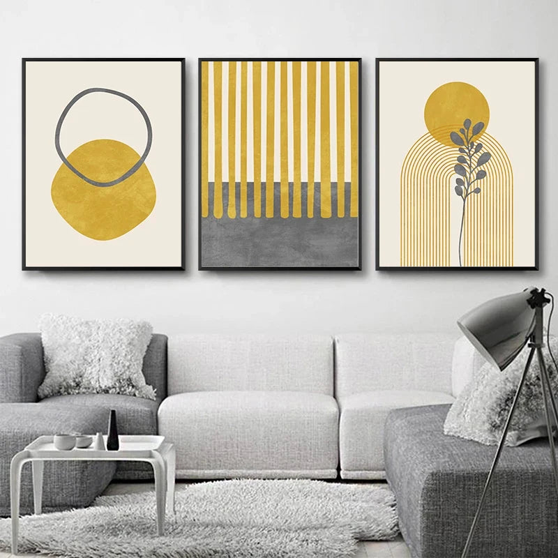 Three abstract art prints on a wall above a gray sofa in a living room.
