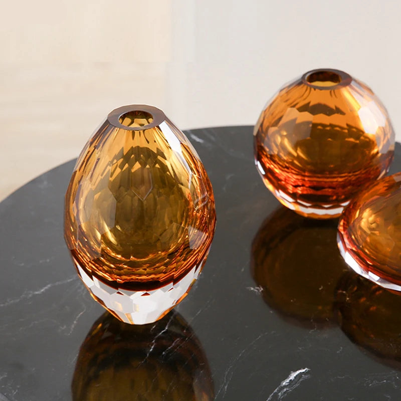 Two amber-coloured glass vases on a reflective surface with a neutral background