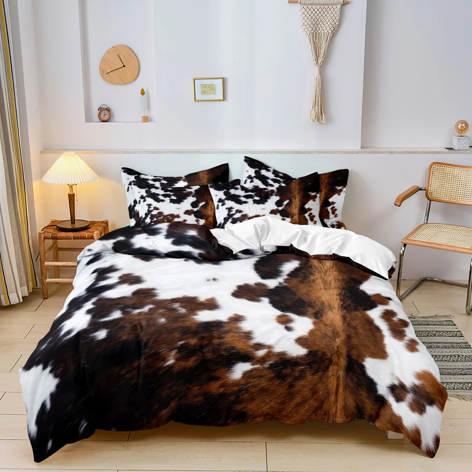 Brown, black, and white cow-print 3-piece bedding set with matching pillowcases in a neutral bedroom.