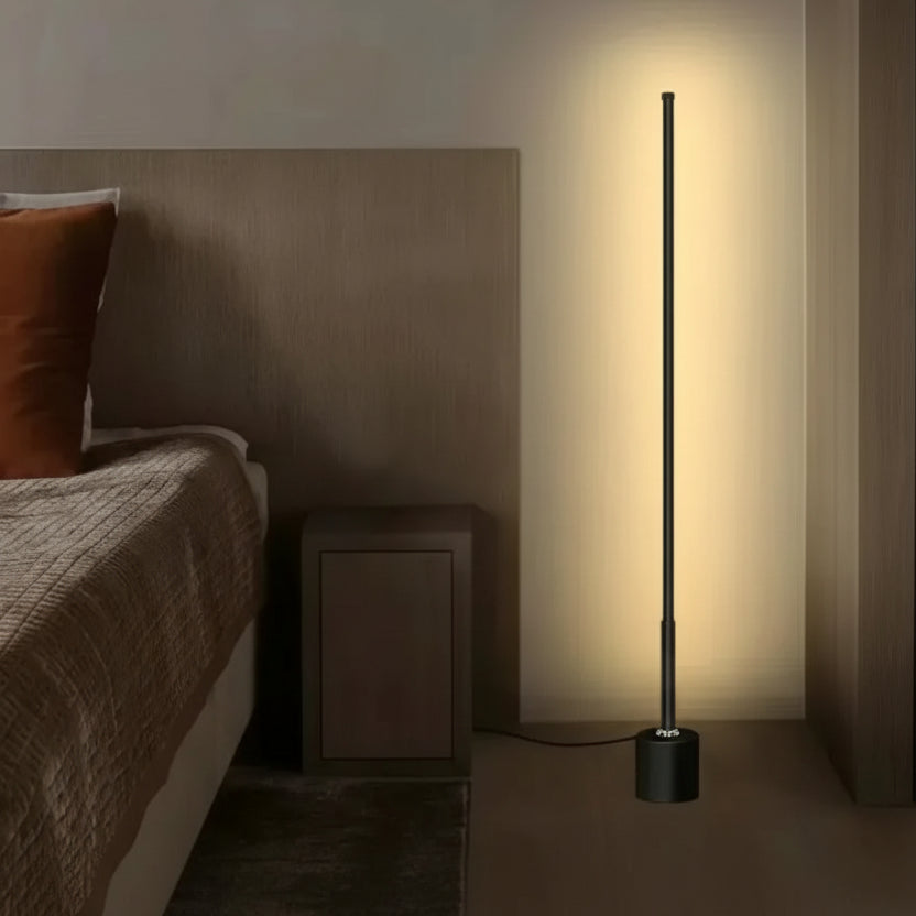 Slim black LED floor lamp casting warm ambient wall light