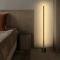 Slim black LED floor lamp casting warm ambient wall light