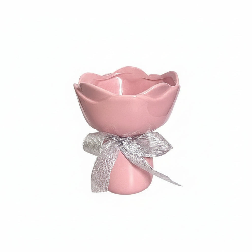 Pink ceramic flower-shaped vase with a silver bow on a white background.
