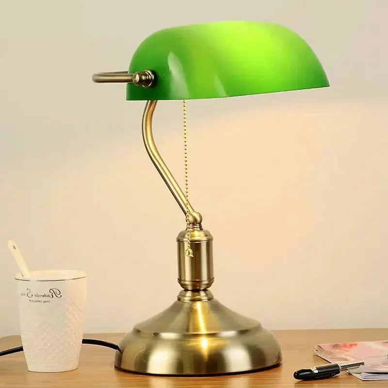 Green glass banker-style desktop lamp with antique brass metal base and pull-chain detail