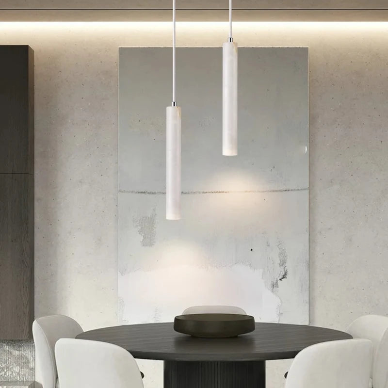 Modern dining area with a round table and white chairs, featuring pendant lights.