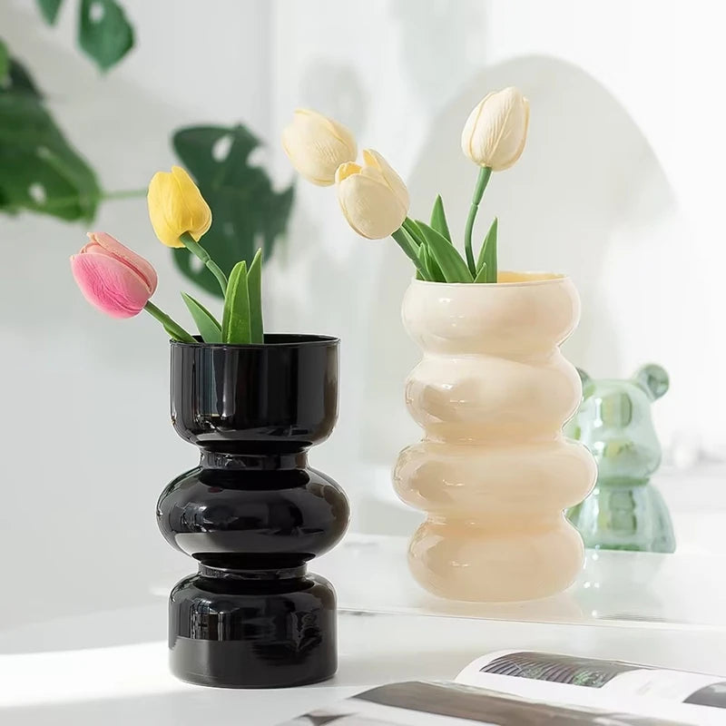 Two vases, black and yellow with tulips on a white surface