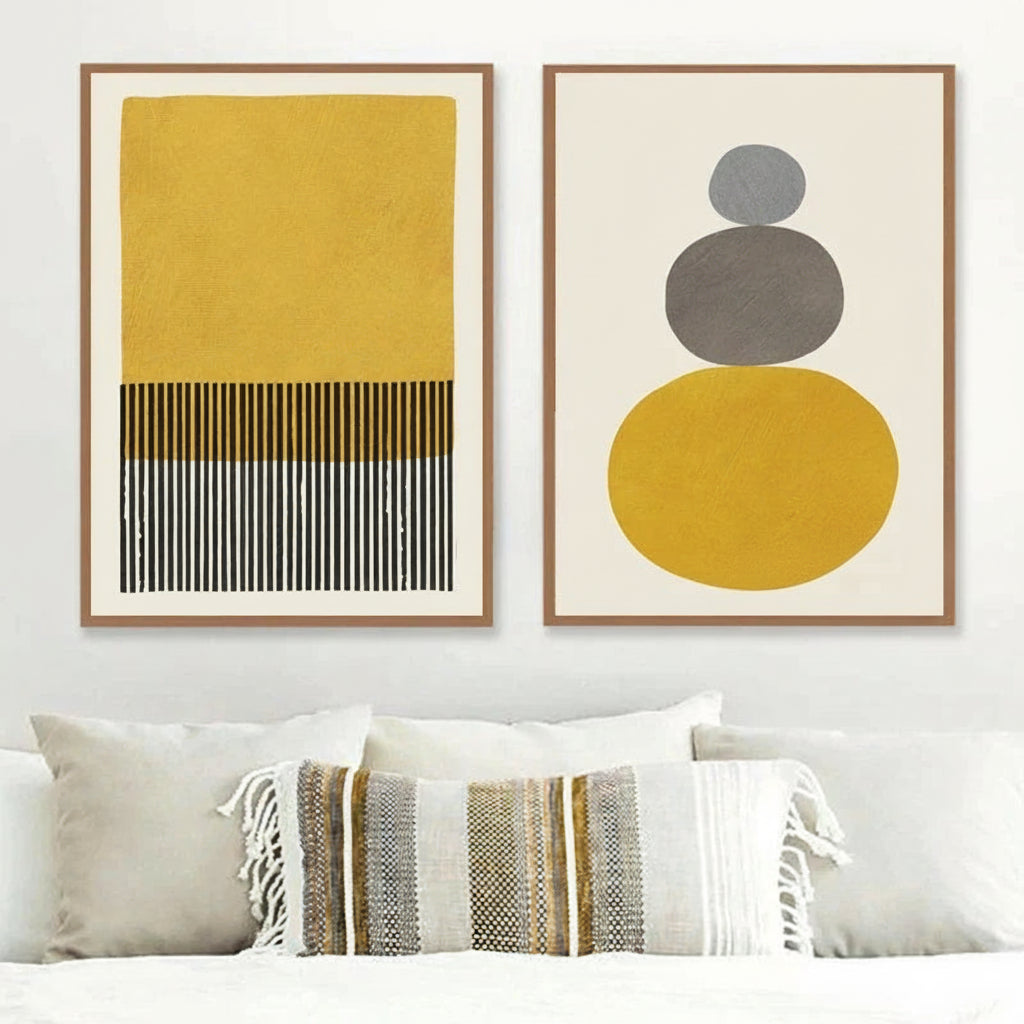 Two abstract art prints on a wall above a sofa with a striped throw.